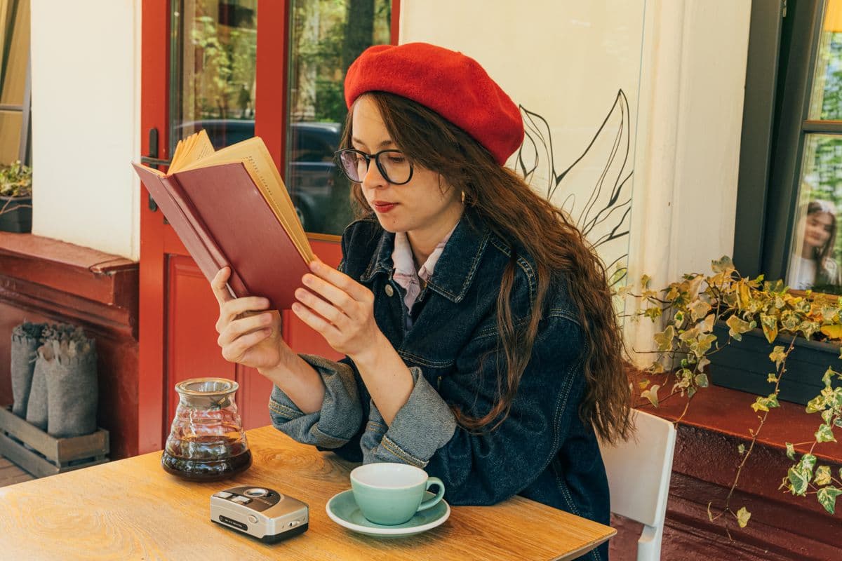 Personne souriante, savourant un livre dans un café