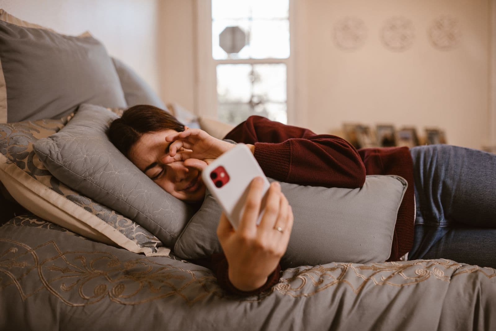 Personne allongée dans son lit, lisant sur son téléphone